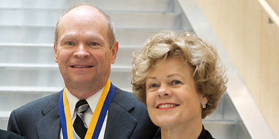 John and Barbara Bruning smile in front of a large staircase.