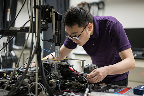 Graduate student Zhengdong Gao adjusts a new "all in one" microcomb laser device in a lab.