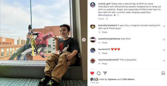 young smiling boy looks out hospital window to see Spider-Man