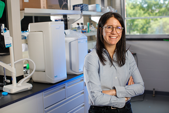Assistant Professor Allison Lopatkin stands with her arms crossed in her chemical engineering laboratory. 