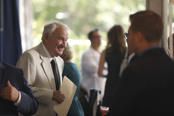 Tom Golisano talks with people during a press conference.