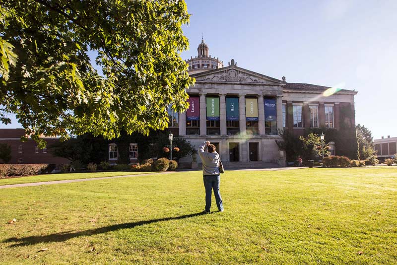 woman takes a picture of Rush Rhees Library