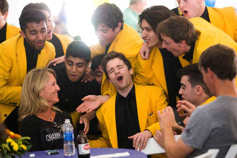Yellowjackets a cappella group sings to a woman sitting at a table