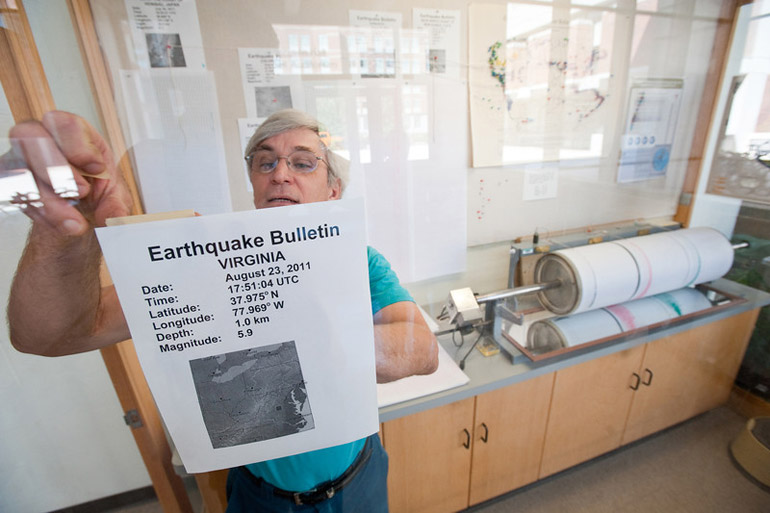 man hangs sign with information about earthquake