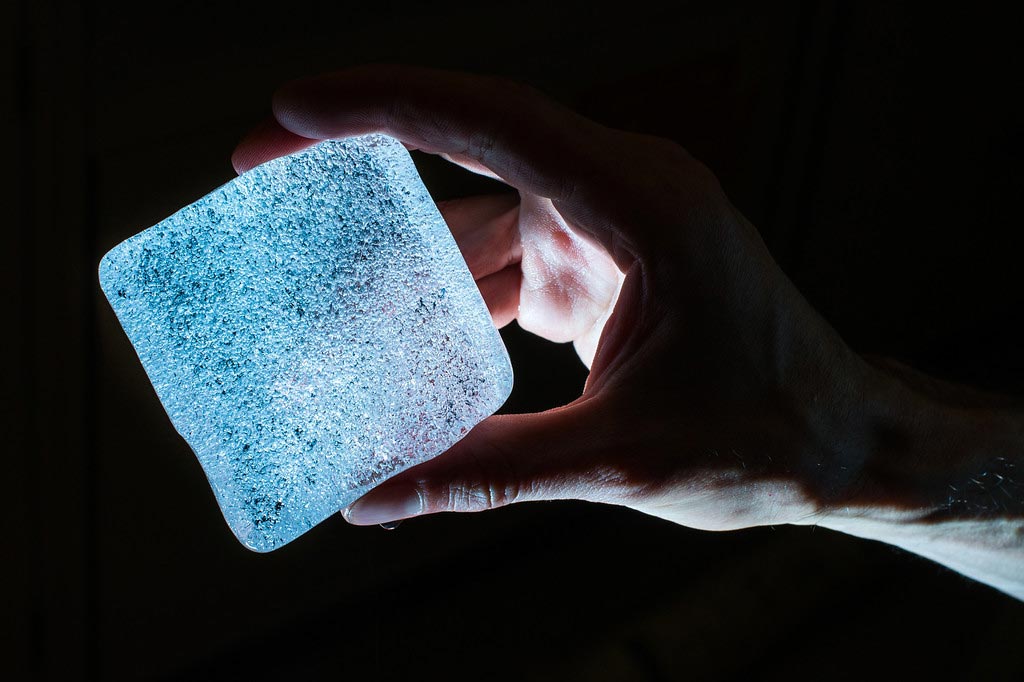 hand holds a glowing cube of ice