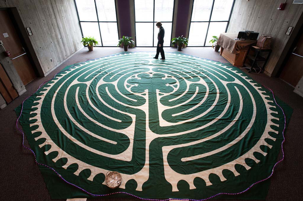 woman walks around a prayer rug shaped like a labyrinth