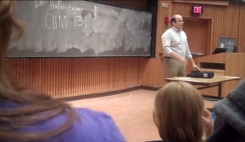 student standing in front of a blackboard in a lecture hall