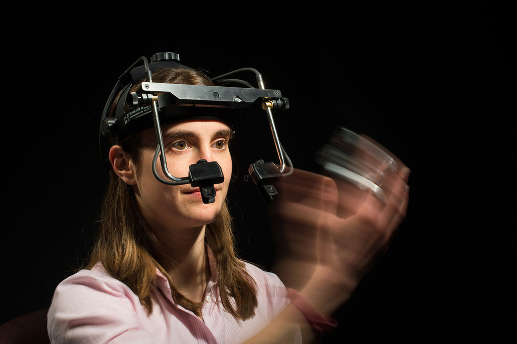student wearing an eye-traching device on her head and waving her hand in front of her face