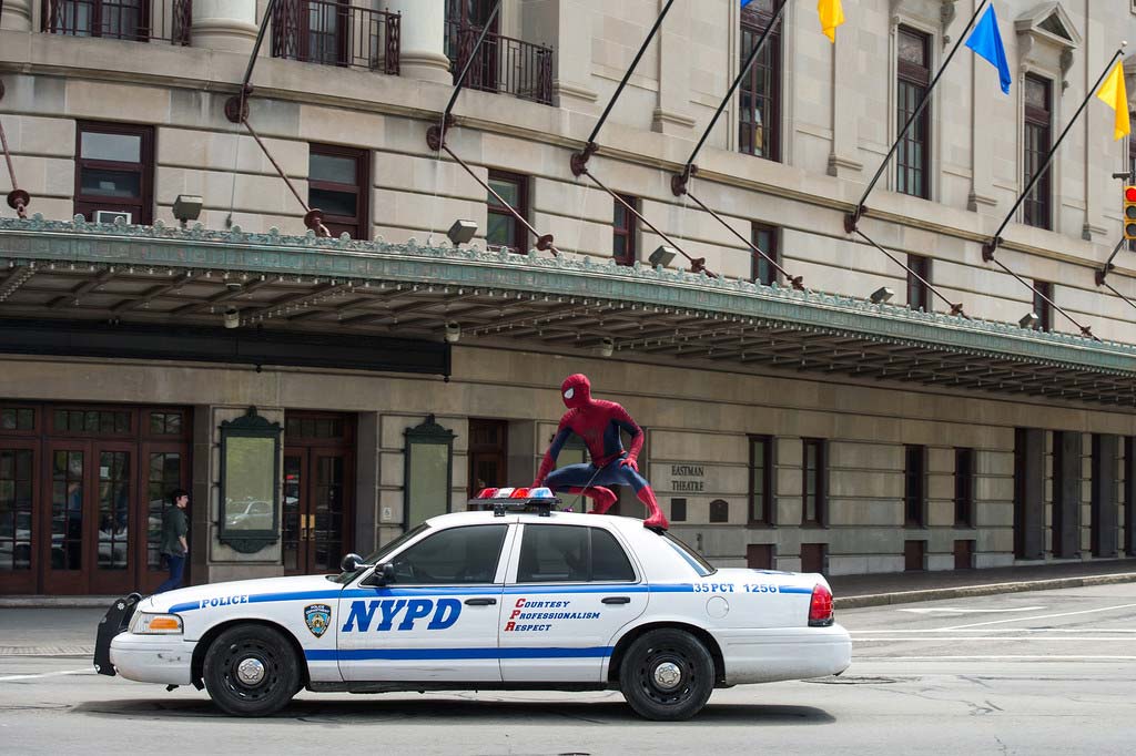Spiderman atop police car in front of Eastman Theater