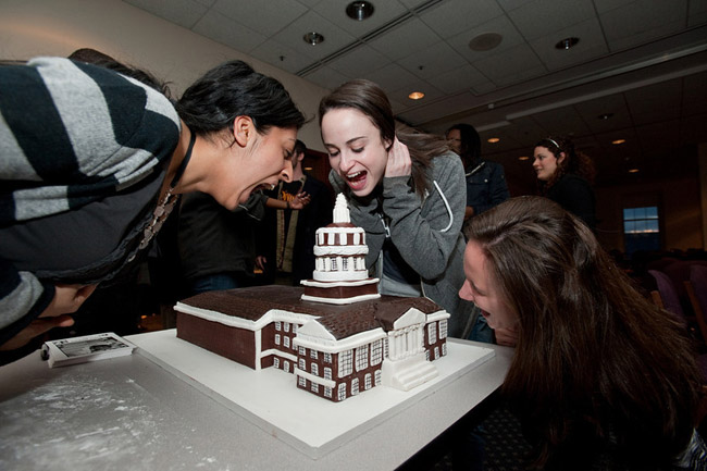 students pretend to eat Rush Rhees Library cake