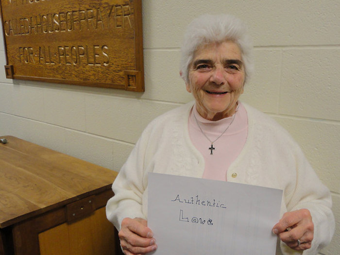 student holding sign that reads AUTHENTIC LOVE