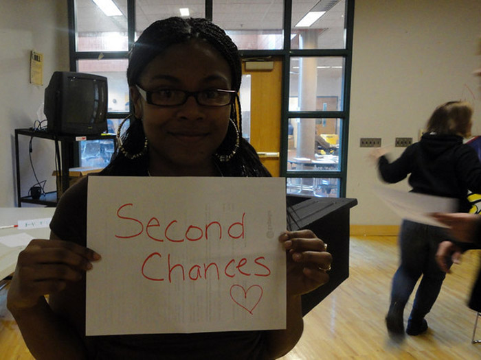 student holding sign that reads SECOND CHANCES