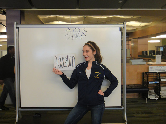 student holding sign that reads AN EDUCATION