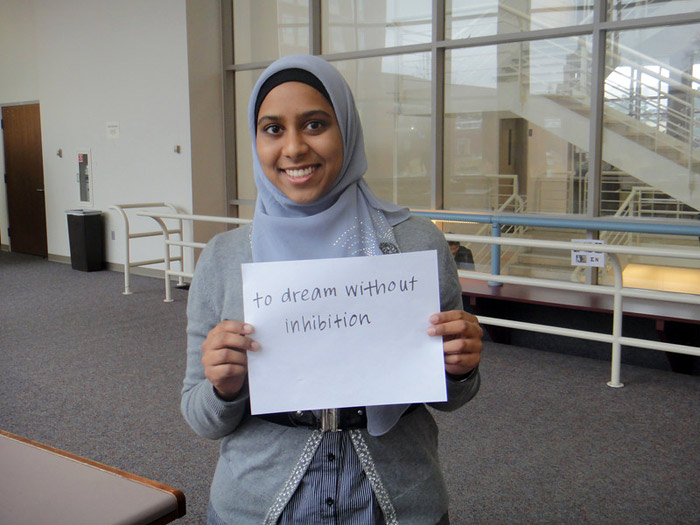 student holding sign that reads TO DREAM WITHOUT INHIBITION