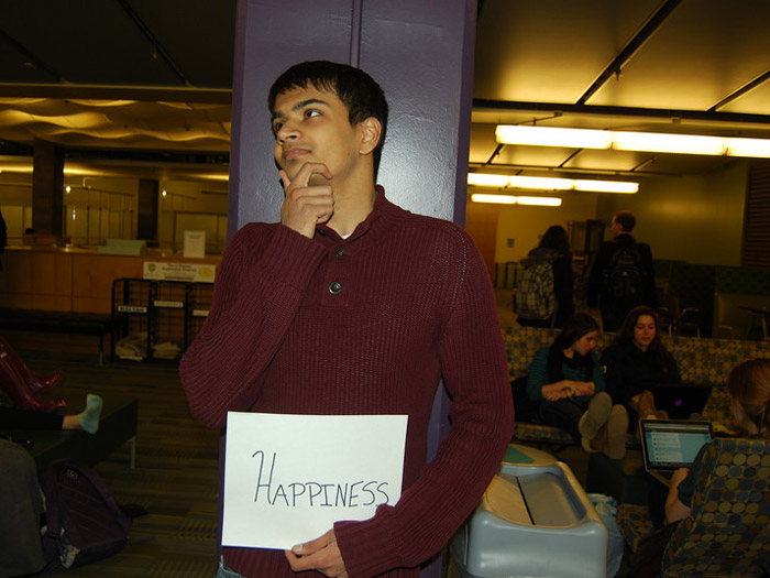 student holding sign that reads HAPPINESS