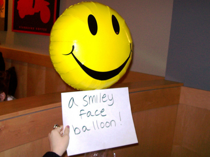 student holding sign that reads A SMILEY FACE BALLOON