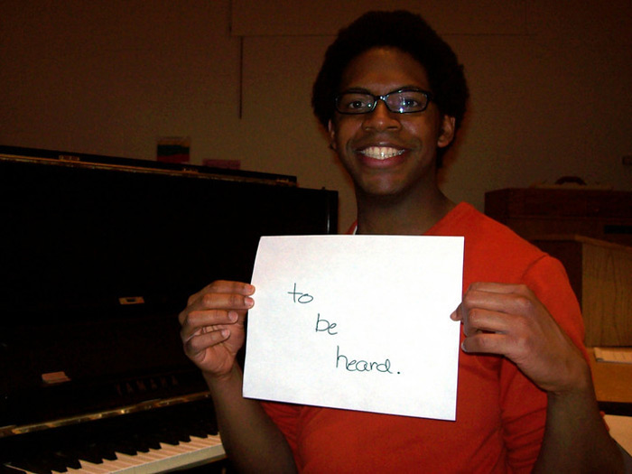 student holding sign that reads TO BE HEARD