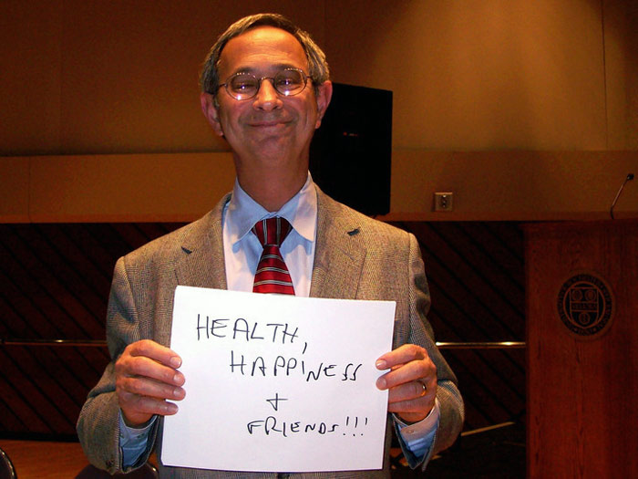 student holding sign that reads HEALTH, HAPPINES, AND FRIENDS