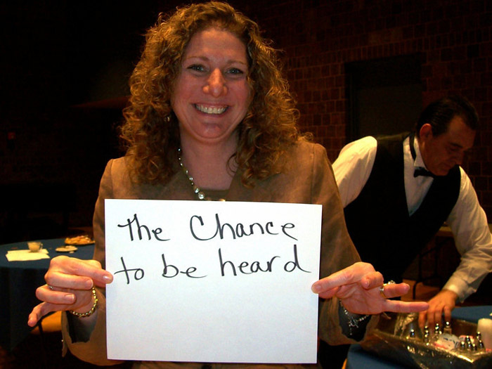 student holding sign that reads THE CHANCE TO BE HEARD