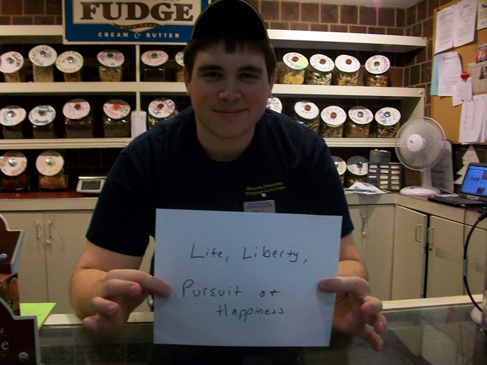 student holding sign that reads LIFE, LIBERTY, AND THE PURSUIT OF HAPPINESS