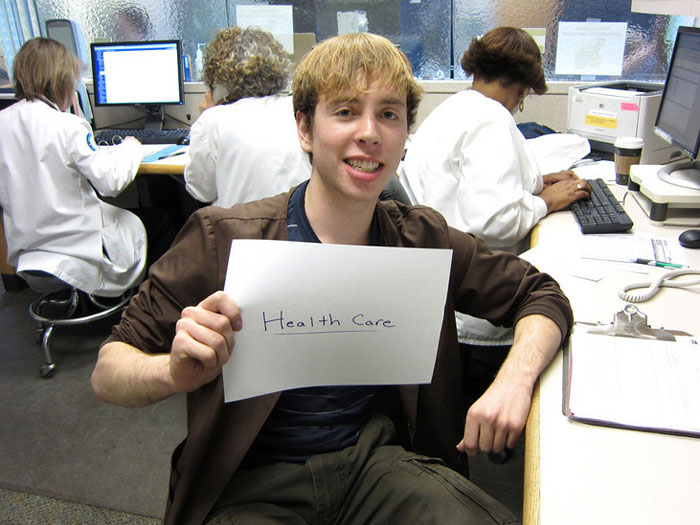 student holding sign that reads HEALTH CARE