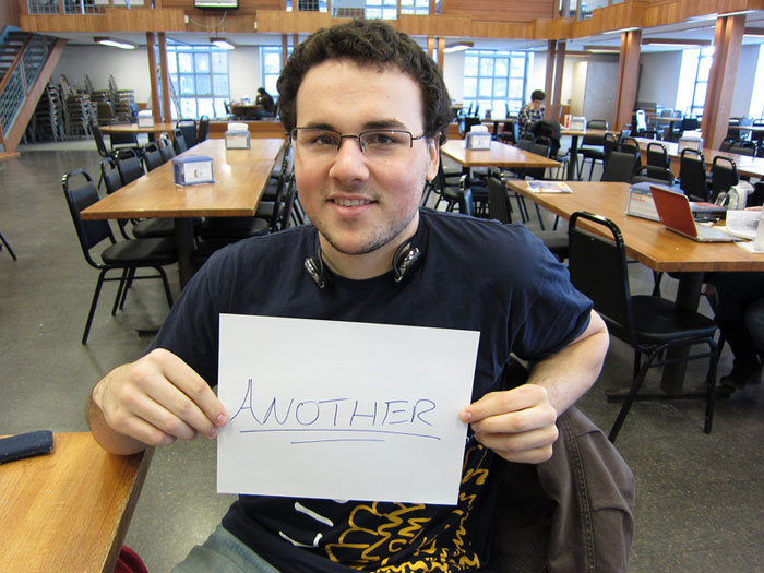 student holding sign that reads ANOTHER