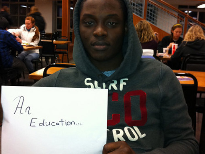 student holding sign that reads AN EDUCATION