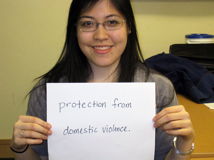 student holding sign that reads PROTECTION FROM DOMESTIC VIOLENCE