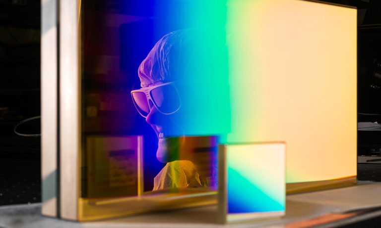 womans face wearing laser goggles and reflected in the glass of a rectangular prism