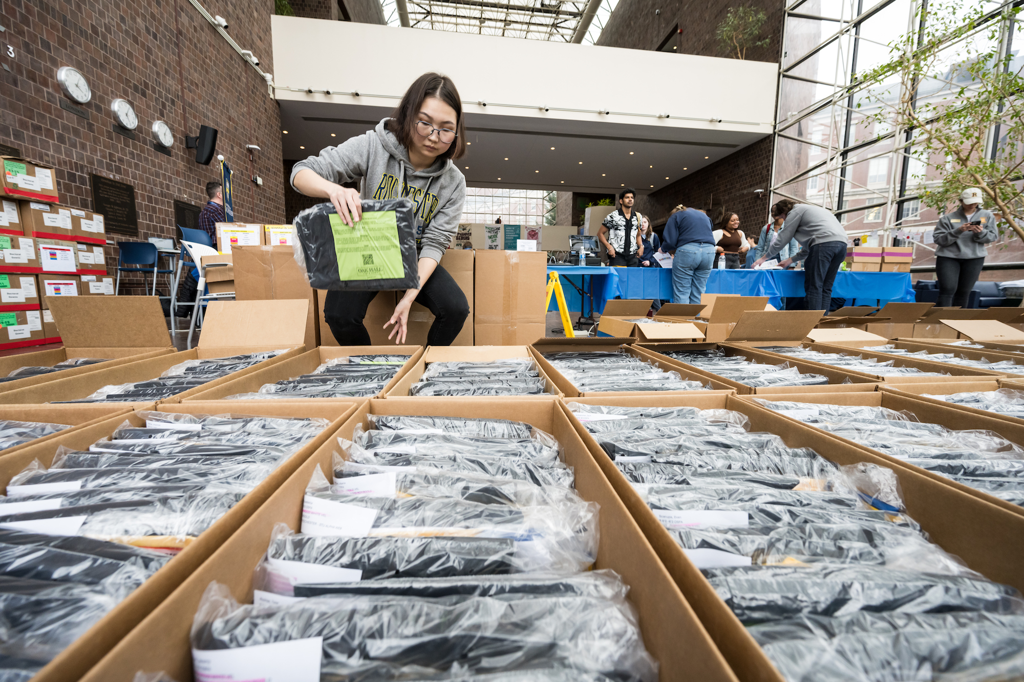 Student employee sorts through boxes of regalia
