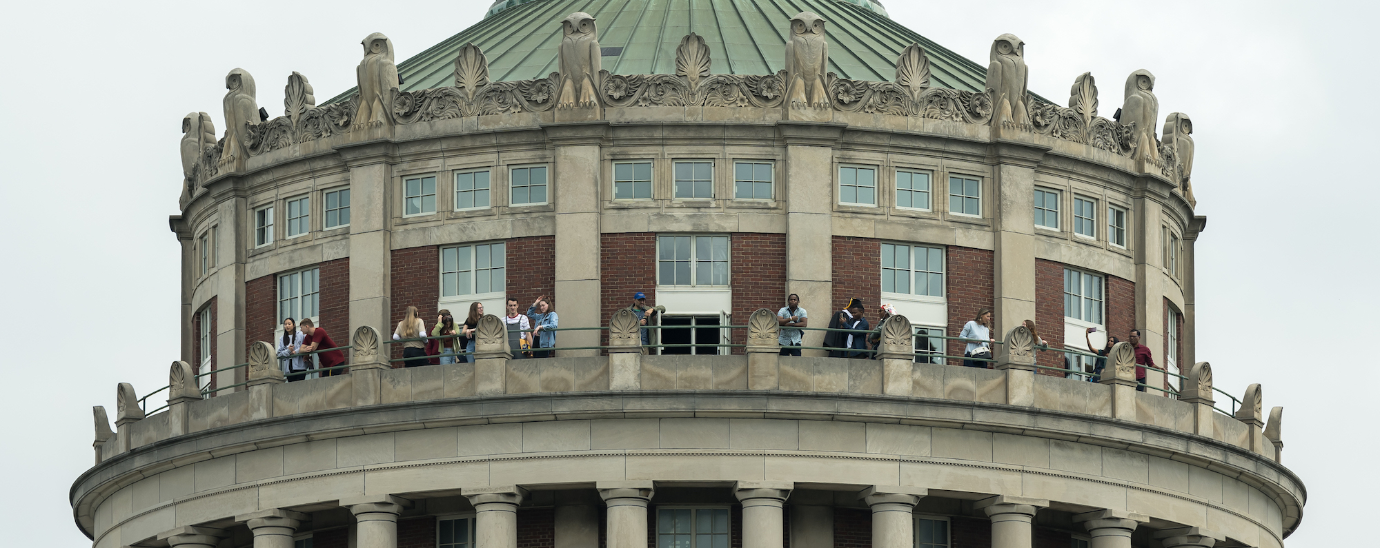 A group of people at the top of Rush Rhees Library Tower, photographed from below