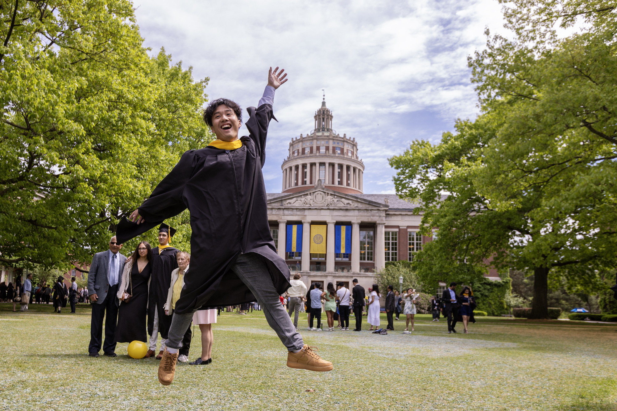Student in graduation regalia leaps in happiness