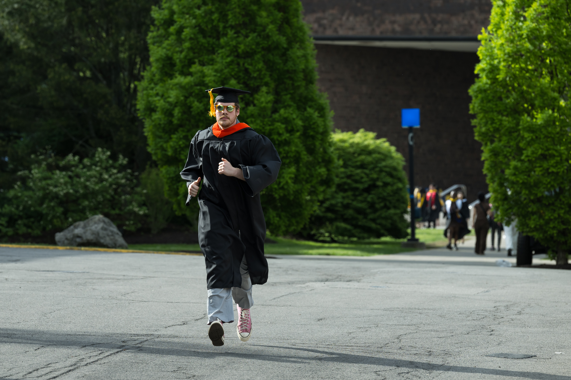 A student in graduation regalia, running