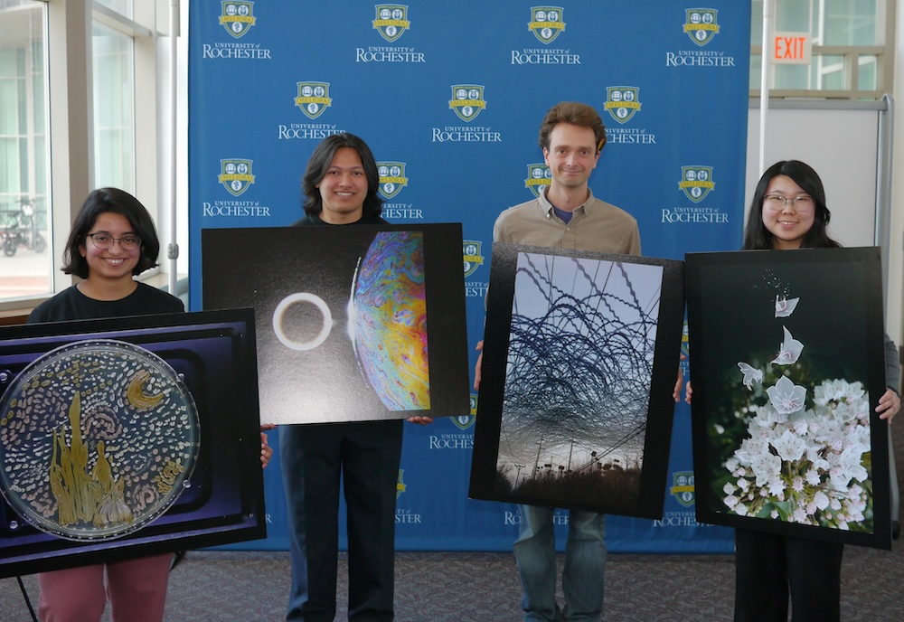 four students hold large posters of their award-winning images.