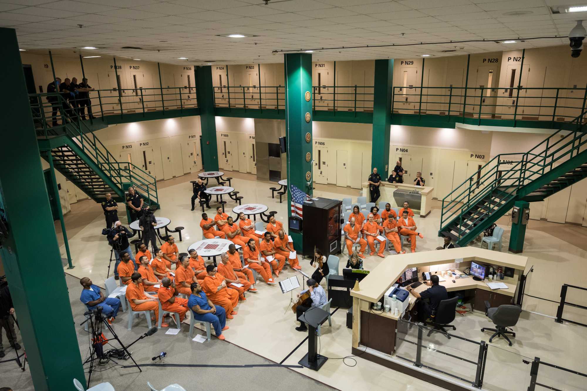 Overhead view of incarcerated people in orange jumpsuits seated for a performance by the ROC City Concerts musicians.
