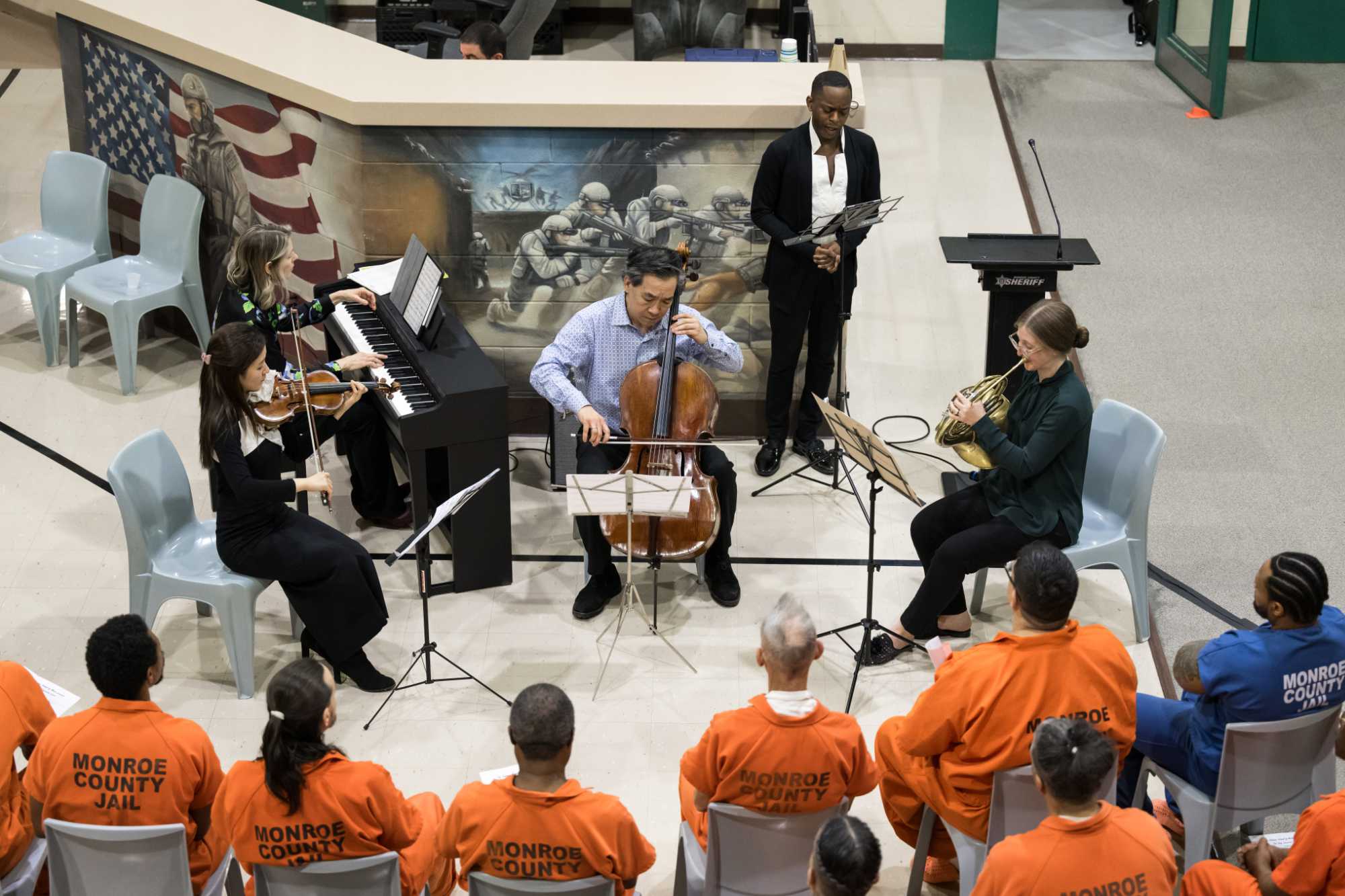 ROC City Concert musicians play their classical music instruments for incarcerated people who are seen from behind.