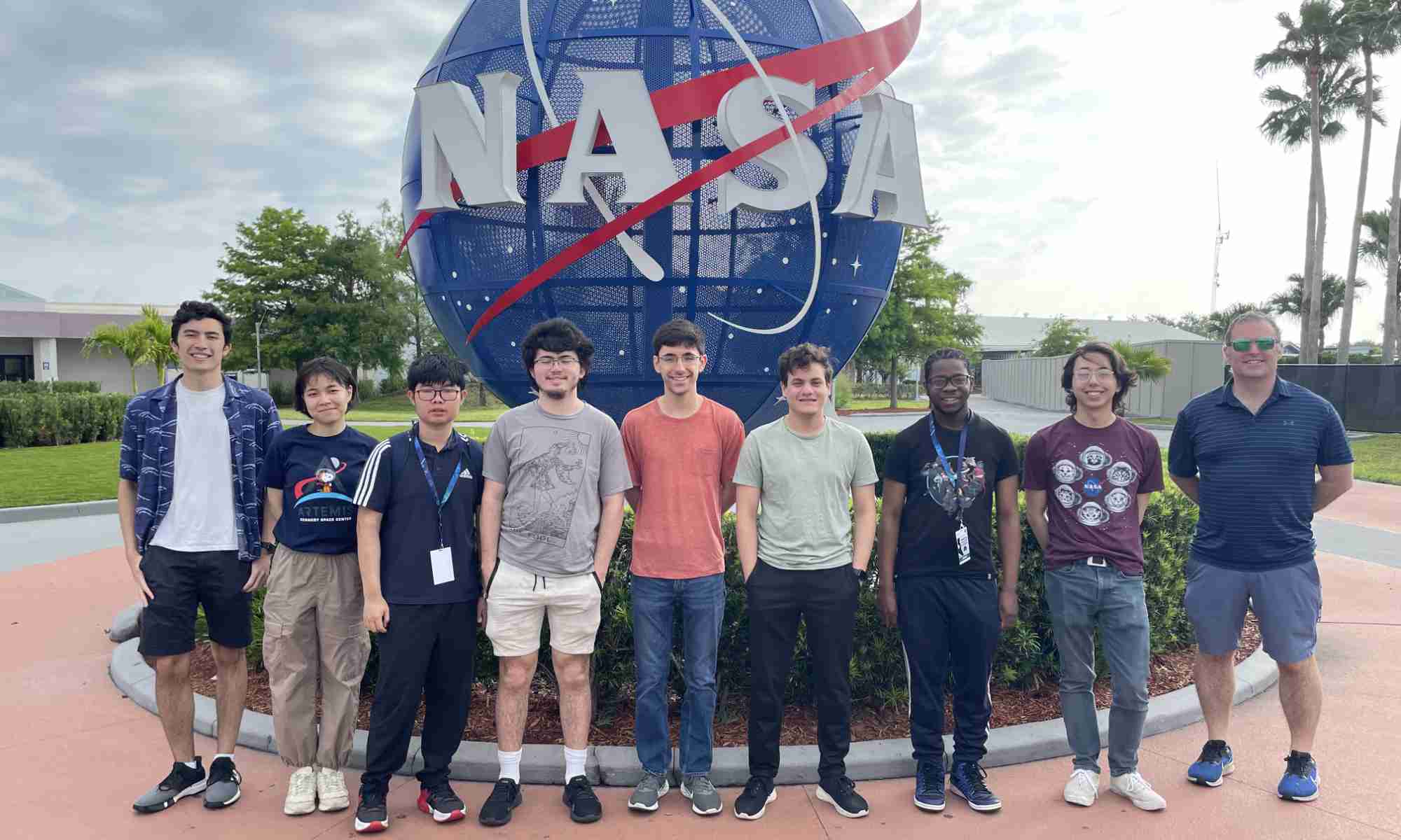 University of Rochester undergraduate engineering students and their advisor pose for a photo in front of the iconic NASA sphere.