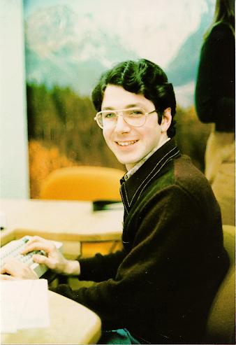 Old color photo of Rick Rashid as a graduate student sitting at an early computer.