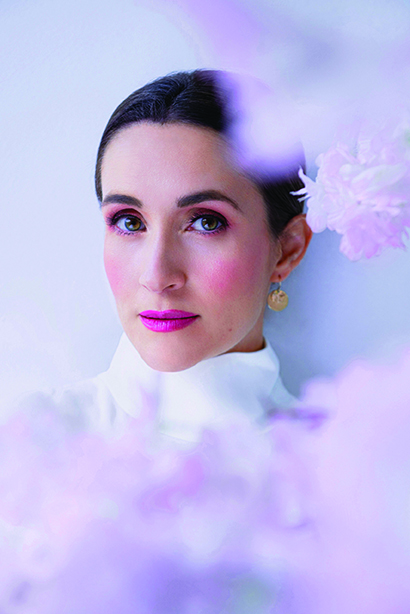 Closeup of Erin Morley's face, makeup and against pink background.