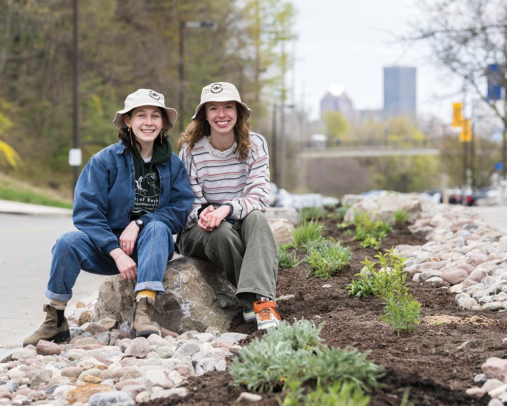 photo of two students sitting by bee pollinator garden