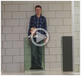 boy standing behind a glass cloaking device