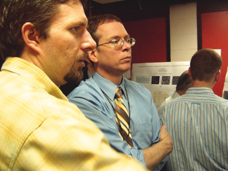 Two people listening to a student presentation.
