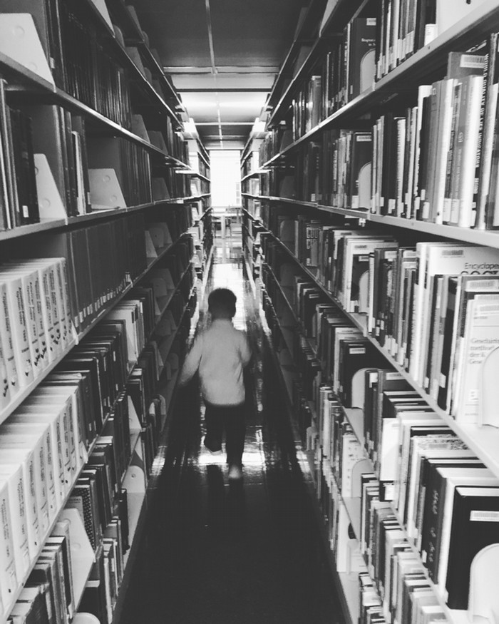 Library with a kids running through in greyscale.