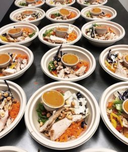 lined up bowls of prepared foods (salads with chicken)