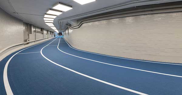 blue indoor track with three lanes, white cinderblock walls
