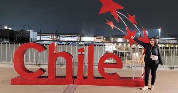 Pilar Osorio-Godoy standing in front of a sign that reads "Chile"