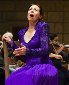 woman in purple dress singing seating in front of orchestra