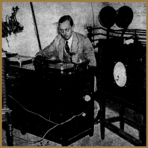 man sits at recording table surrounded by equipment
