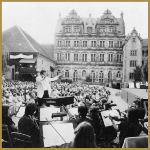 image of outside concert, full orchestra, in front of historical building
