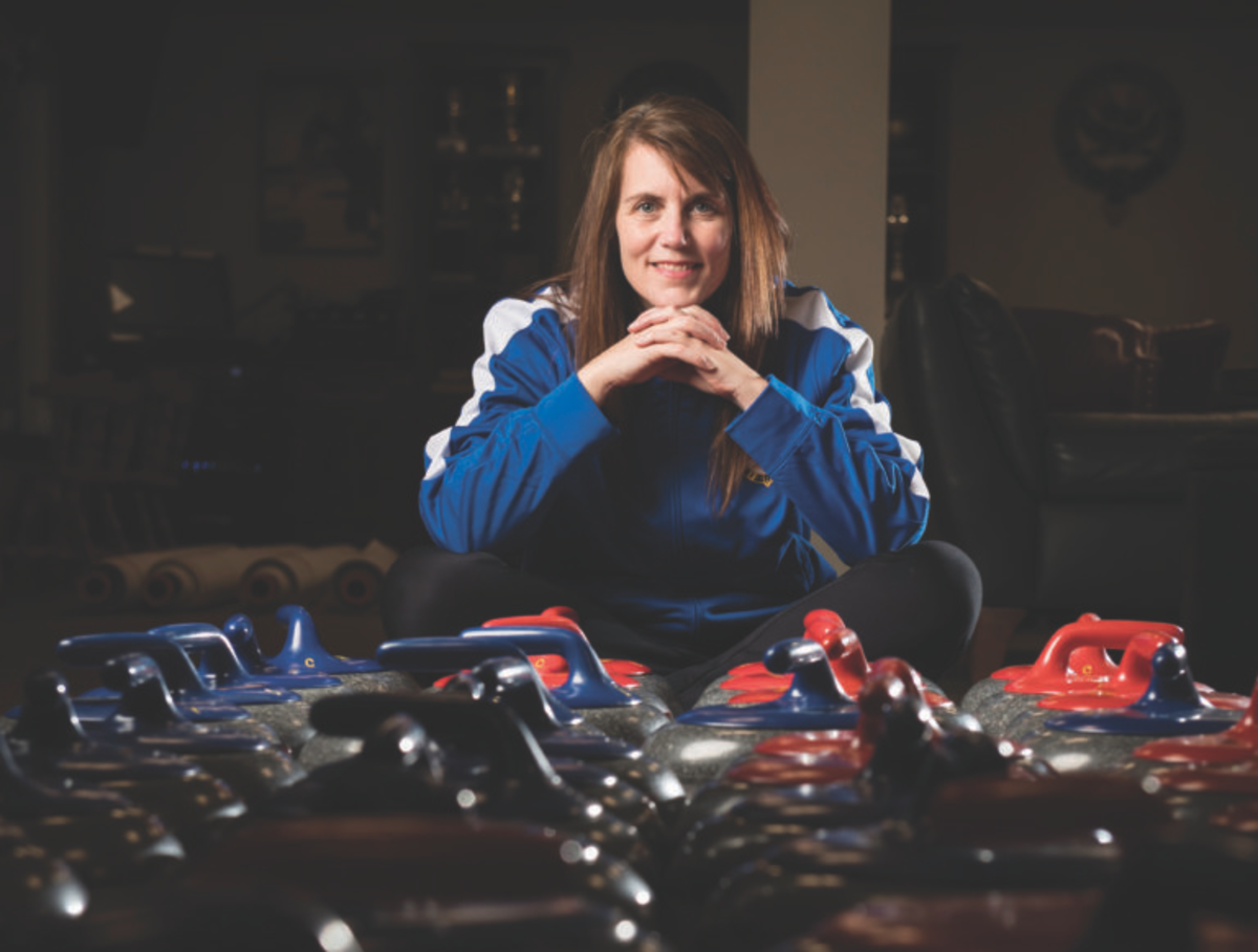 Image: Caitlin Costello Pulli ’97 sitting behind multiple curling stones on the floor